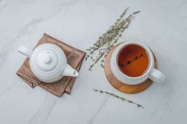 Thyme herbal tea, view from high angle on white cup with tea and kettle - Fotoğraf, Görsel