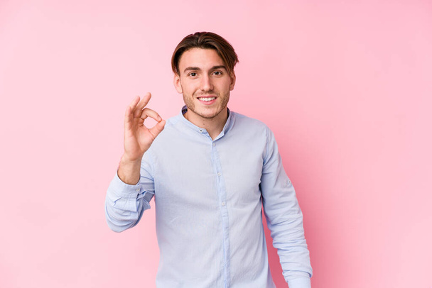 Young caucasian man posing in a pink background isolated cheerful and confident showing ok gesture. - Photo, Image