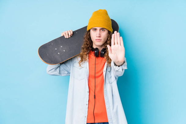 Young caucasian skater man isolated standing with outstretched hand showing stop sign, preventing you. - Foto, Imagen