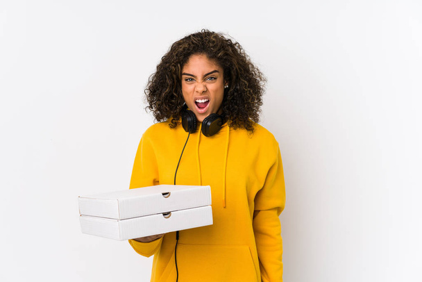 Young african american student woman holding pizzas screaming very angry and aggressive. - Foto, Bild