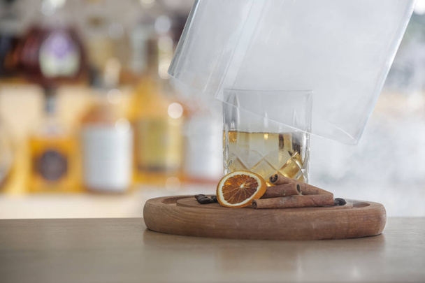 Hazy Whiskey Cocktail, A glass of smoked whiskey served with a slice of dry orange and cinamon stick - Fotografie, Obrázek