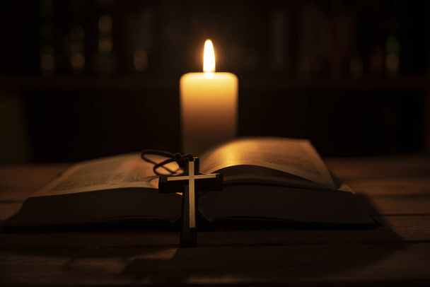 bible is lying open on a table and a candle is burning - Fotoğraf, Görsel