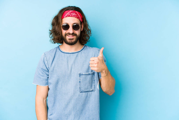 Joven hombre de pelo largo con una mirada hipster festival aislado sonriendo y levantando el pulgar hacia arriba
 - Foto, imagen