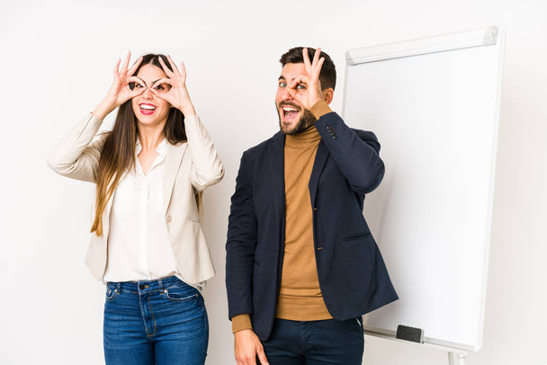 Jeune couple d'affaires caucasien isolé montrant signe OK sur les yeux
 - Photo, image
