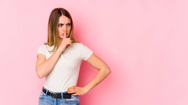 Young caucasian woman isolated on pink background keeping a secret or asking for silence. - Photo, Image