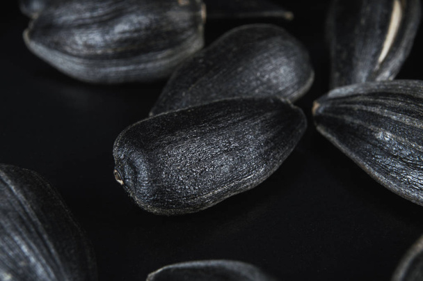 Чорне насіння соняшнику в макросі ізольовано на чорному тлі. Їжа фото з текстурою крупним планом
. - Фото, зображення