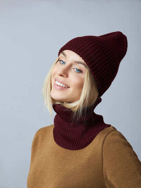 Woman in spring clothes, Snood scarf, hat and gloves. The girl is blonde with blue eyes. Warm clothing for cold spring weather - Foto, afbeelding