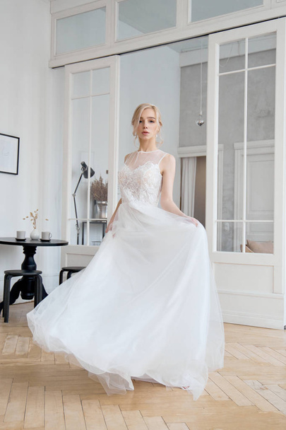 Blonde girl in a beautiful white wedding dress. A woman bride is waiting for the groom before the wedding - Фото, зображення