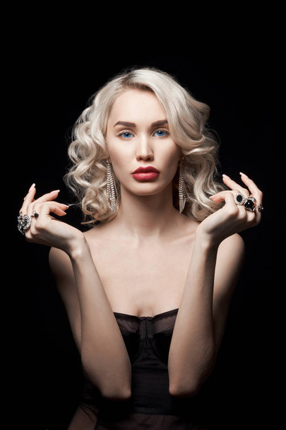 Beauty fashion woman with jewelry on her hands, wavy hair. Portrait of a blonde girl with rings on her fingers, beautiful makeup on her face, perfect hair styling - Фото, изображение
