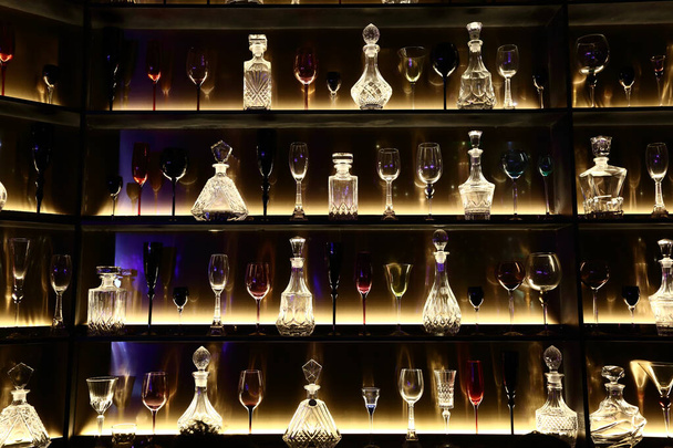 Muitos mostram garrafas vazias e vidro de vinho decorativo na prateleira retroiluminada, noite clube de volta aro luz fundo papel de parede fundo
 - Foto, Imagem