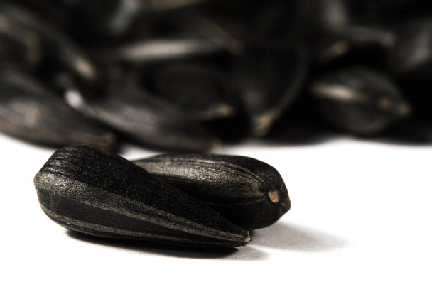 Чорне насіння соняшнику в макросі ізольовано на білому тлі. Їжа фото з текстурою крупним планом
. - Фото, зображення