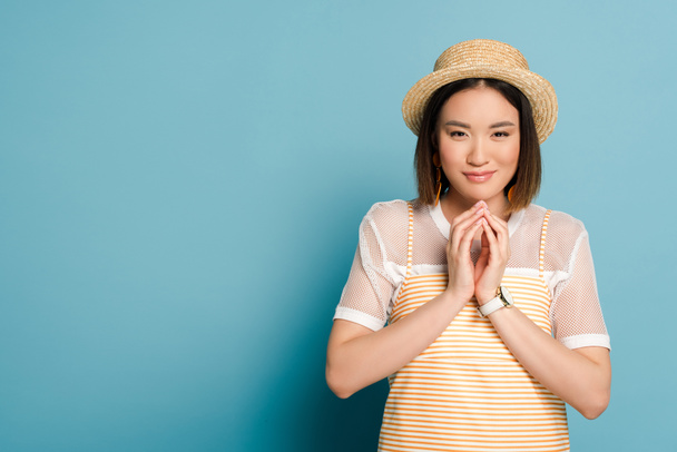 cunning asian girl in striped yellow dress and straw hat on blue background - Φωτογραφία, εικόνα