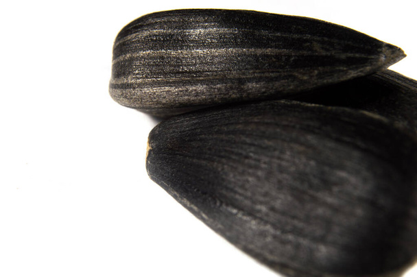 Чорне насіння соняшнику в макросі на білому тлі. Їжа фото з текстурою крупним планом
. - Фото, зображення