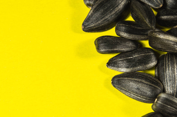 Sarı arka planda izole edilmiş makrodaki siyah ayçiçeği tohumları. Yemek fotoğrafı, dokusu yakın çekim.. - Fotoğraf, Görsel