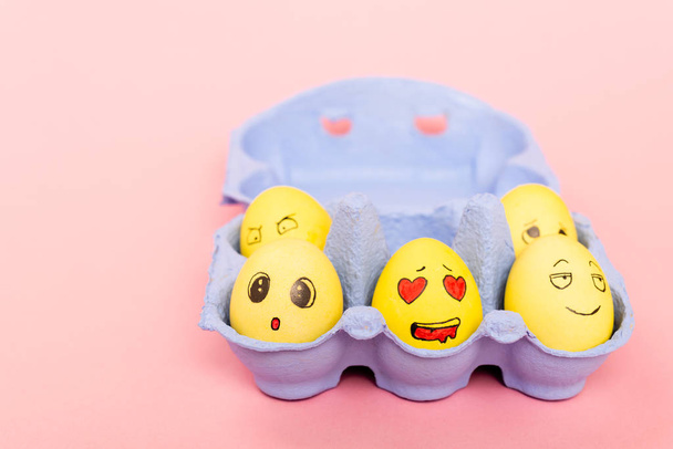 Επιλεκτική εστίαση των βαμμένων αυγών του Πάσχα με εκφράσεις του προσώπου στο δίσκο αυγών σε ροζ  - Φωτογραφία, εικόνα