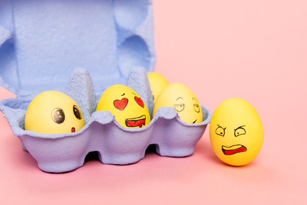 Huevos de pollo divertidos con expresiones faciales en bandeja de huevo en rosa, concepto de Pascua
 - Foto, imagen