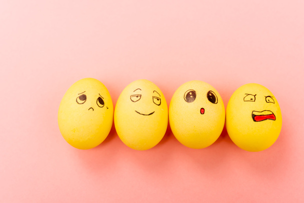 Top view of Easter eggs with different funny facial expressions on pink background - Photo, Image