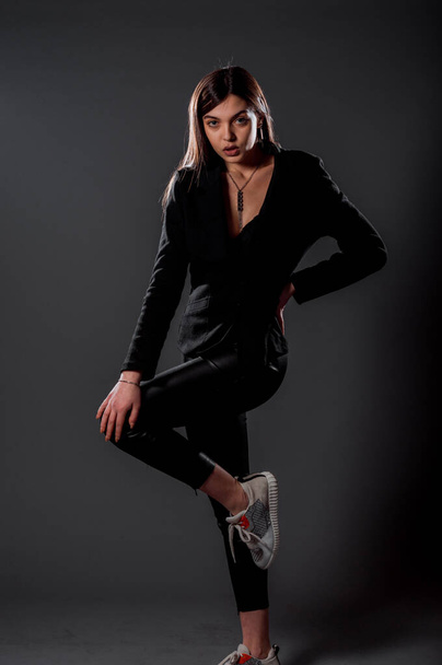 Кузовний знімок холодної сучасної дівчини в чорних верхніх і чорних шкіряних штанях
 - Фото, зображення