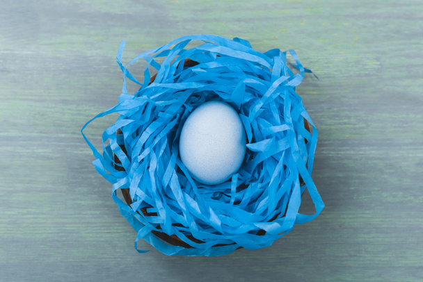 Top view of nest with painted chicken egg on wooden background, easter concept - Photo, image
