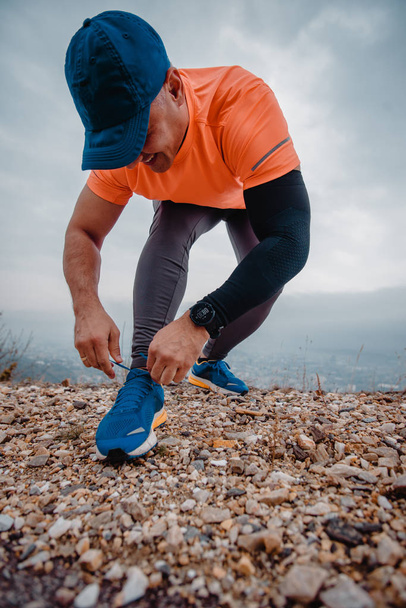 Dobře stavěný zralý běžec utahující tkaničky svých sportovních bot - Fotografie, Obrázek