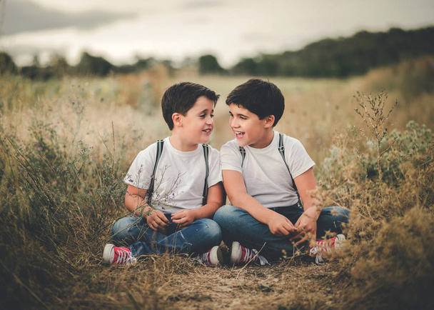 Sonrientes hermanos sentados en el campo al aire libre
 - Foto, imagen