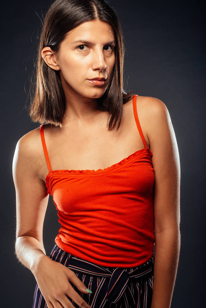 トレンディ現代女性で赤上ポーズに対して暗い背景 - 写真・画像