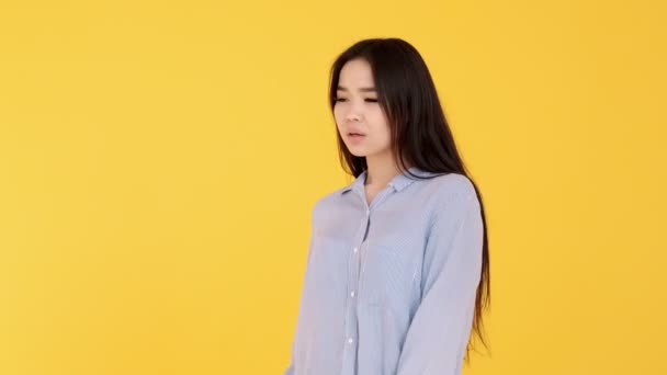 Young Asian girl on yellow background posing and flirting and smiling at camera - Filmagem, Vídeo