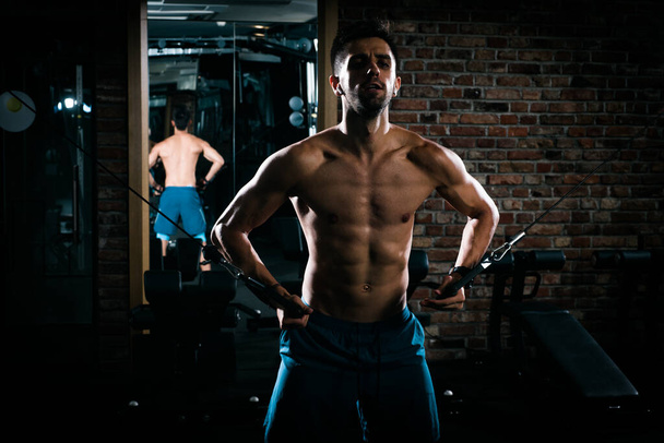 Тонкий м'язистий чоловік робить витяжки без сорочки в спортзалі, зображення з високою контрастністю
 - Фото, зображення