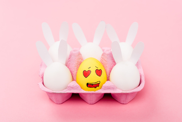 Conigli decorativi e uovo giallo con espressione facciale innamorata su rosa, concetto pasquale
 - Foto, immagini