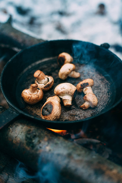 Cogumelos fritos em uma panela na floresta. Comida frita na natureza. Piquenique na floresta de inverno. Cozinhar numa fogueira. Champignon em uma fogueira
. - Foto, Imagem