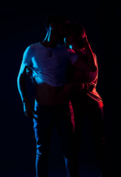 Sensuele liefdevolle man en vrouw poseren tegen een zwarte achtergrond - Foto, afbeelding