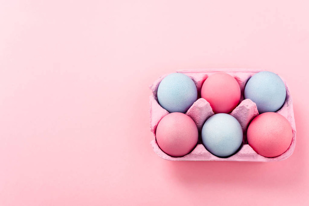Vista de ángulo alto de huevos de Pascua pintados en bandeja de huevo en rosa
  - Foto, Imagen