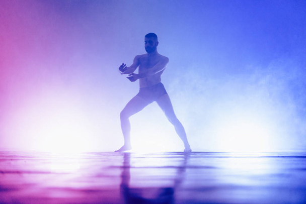 Flexible shirtless man performing an artistic dance movement - Foto, imagen