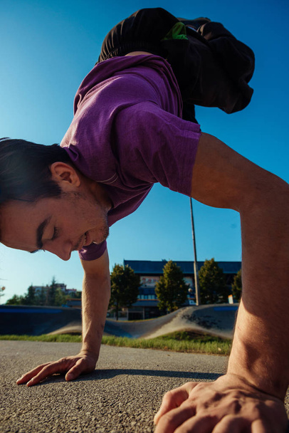 Käsiliike suorittaa nuori urheilullinen kaveri kaupunkialueella - Valokuva, kuva