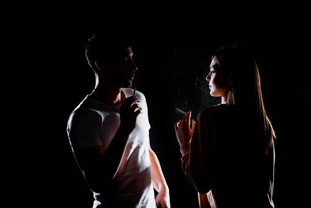 Attractive young man and woman posing against a black background - 写真・画像