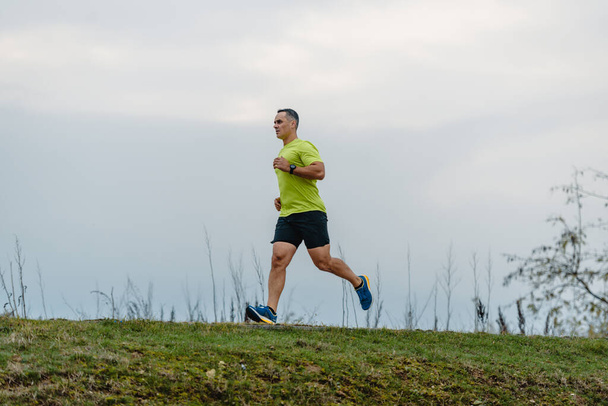 Здоровый мужчина средних лет в спортивной одежде готовится к пробежке - Фото, изображение