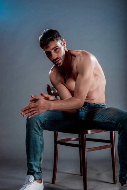 Studio fashion portrait of a half naked man sitting on a chair - Foto, afbeelding