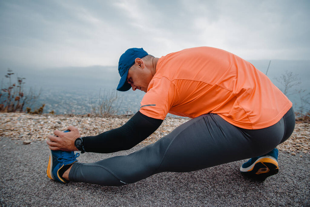 Muskularny mężczyzna noszący sportowe ubrania podczas przygotowań do ćwiczeń biegowych - Zdjęcie, obraz