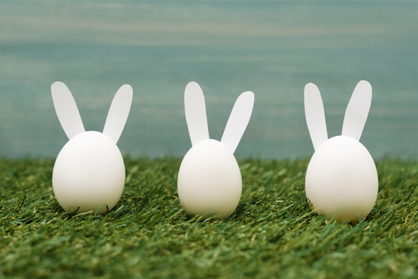 Conejitos blancos decorativos en la hierba, concepto de Pascua
 - Foto, imagen