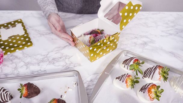 Stap voor stap. Verpakking chocolade gedompelde aardbeien in een papieren doos voor een geschenk. - Foto, afbeelding