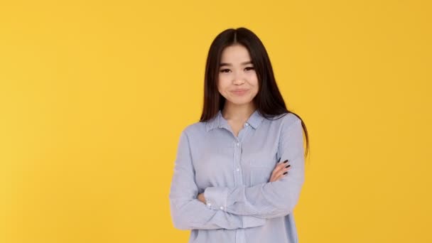 Young Asian girl on yellow background smiling and looking at camera. blue shirt - Filmmaterial, Video