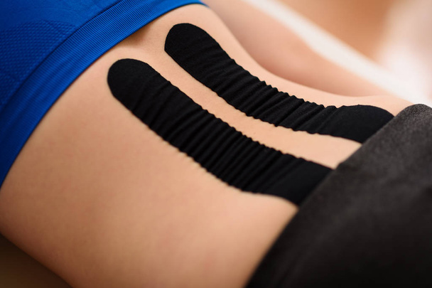 Close up shot of a female patient's lower back with kinesio tape. Kinesiology, physical therapy, rehabilitation concept. Cropped shot close up. - Fotoğraf, Görsel