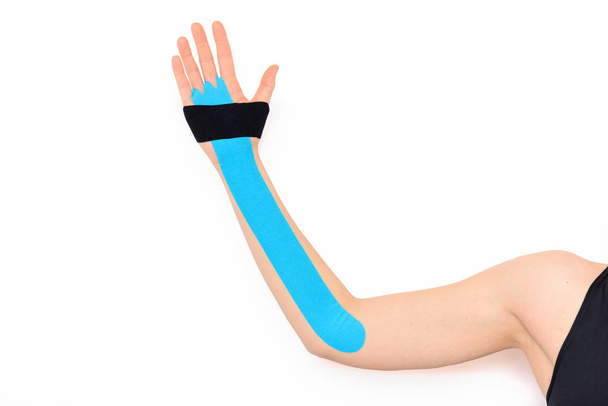 Close up studio shot of a female arm with kinesio tape, isolated over white background. Kinesiology, physical therapy, rehabilitation concept. - Φωτογραφία, εικόνα