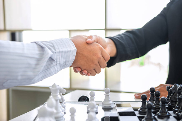 Black and White chess with player, Businessman and Businesswoman shaking hands after end game of thinking strategy to moving chess figure in competition with opposite player and planning. - Photo, Image
