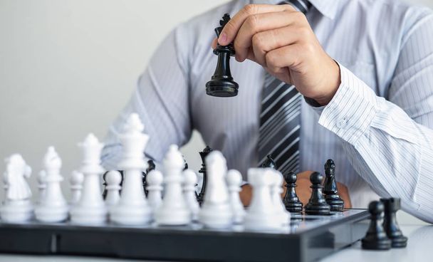 Zwart-wit schaken met speler, Handen van zakenman denken aan bewegende schaakfiguur in concurrentie en planning strategie om succes te spelen voor de overwinning. - Foto, afbeelding