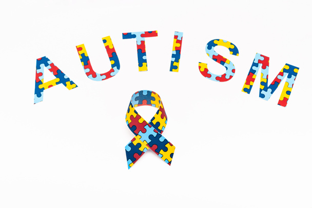 High angle view of Autism puzzle lettering and awareness ribbon isolated on white  - Foto, imagen