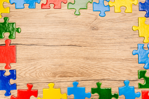 Top view of bright multicolored pieces of puzzle on wooden background, autism concept - Photo, Image