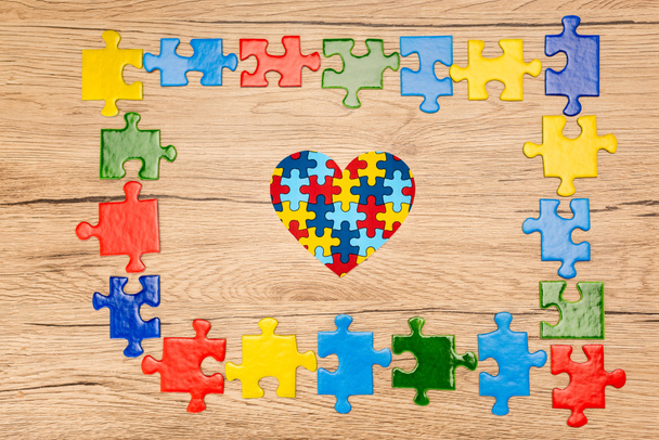 Top view of decorative heart with pieces of puzzle on wooden background, autism concept - Photo, Image