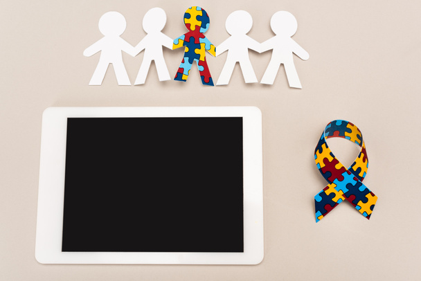 Top view of awareness ribbon, digital tablet and special kid with autism among another on white background - Photo, image