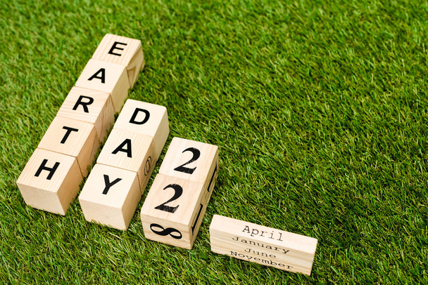 High angle view of cubes with earth day and 22 april lettering on green background - 写真・画像